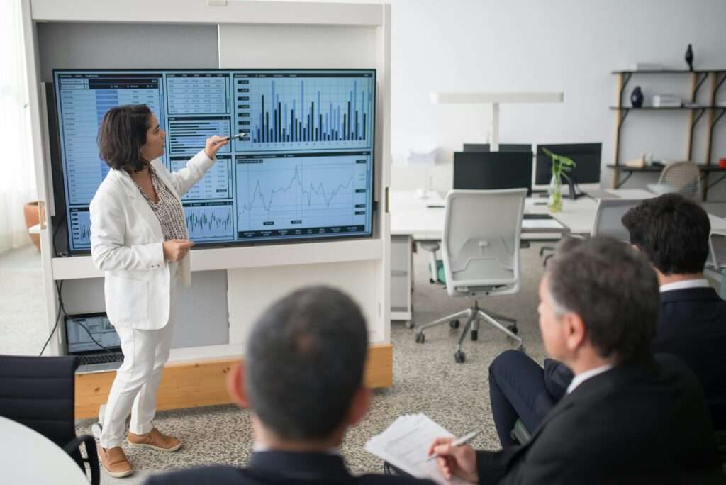 a woman standing in front of a screen with a pen pointing at a graph