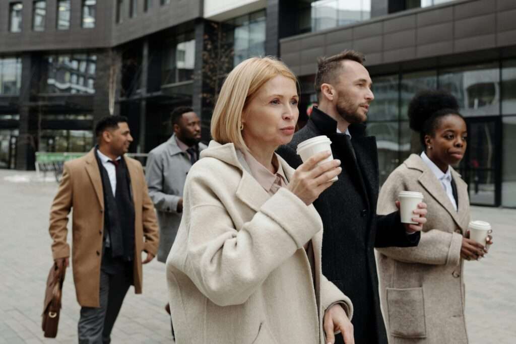 Group of people walking outdoors with coffee. what is queen bee syndrome at work
